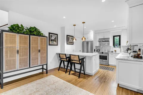 a kitchen with stainless steel appliances kitchen island granite countertop a table chairs and a refrigerator