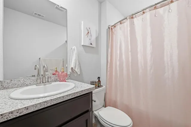 a bathroom with a granite countertop sink toilet and a mirror