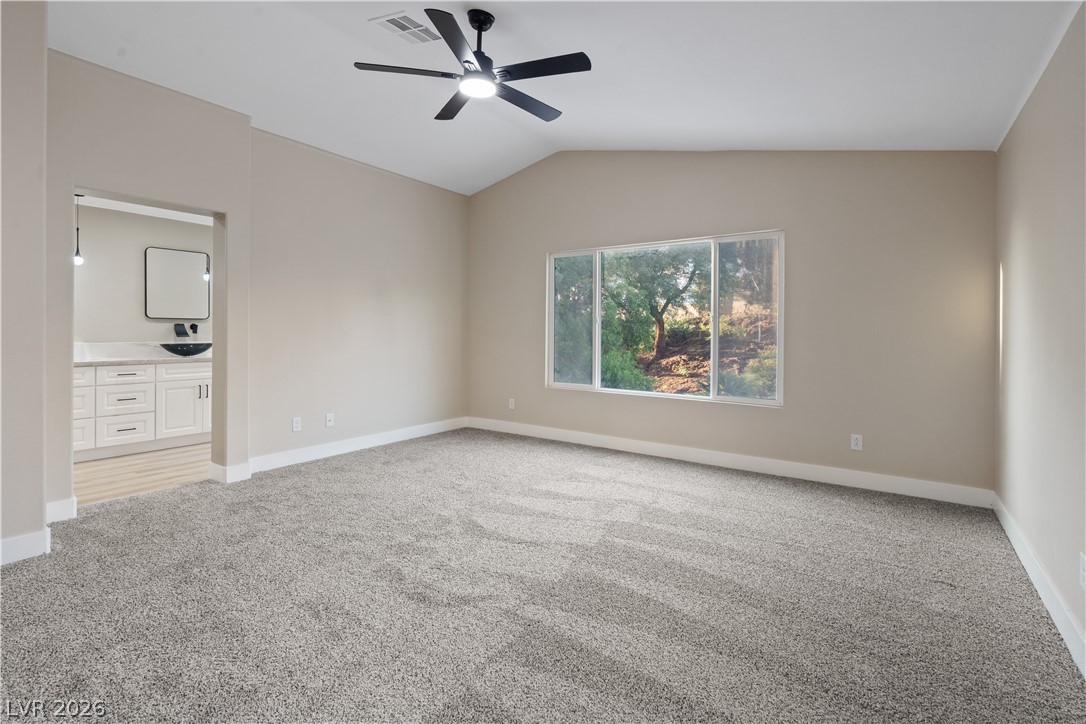 1662 Ravanusa Drive Henderson, NV 89052 - Photo 21 of 74 A spacious primary bedroom features soft carpeting, a ceiling fan, and large windows with hillside views.