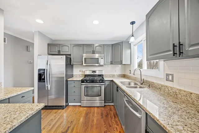 a kitchen with stainless steel appliances granite countertop a sink stove microwave and refrigerator