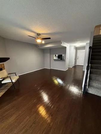 a view of an empty room with wooden floor a ceiling fan and a window