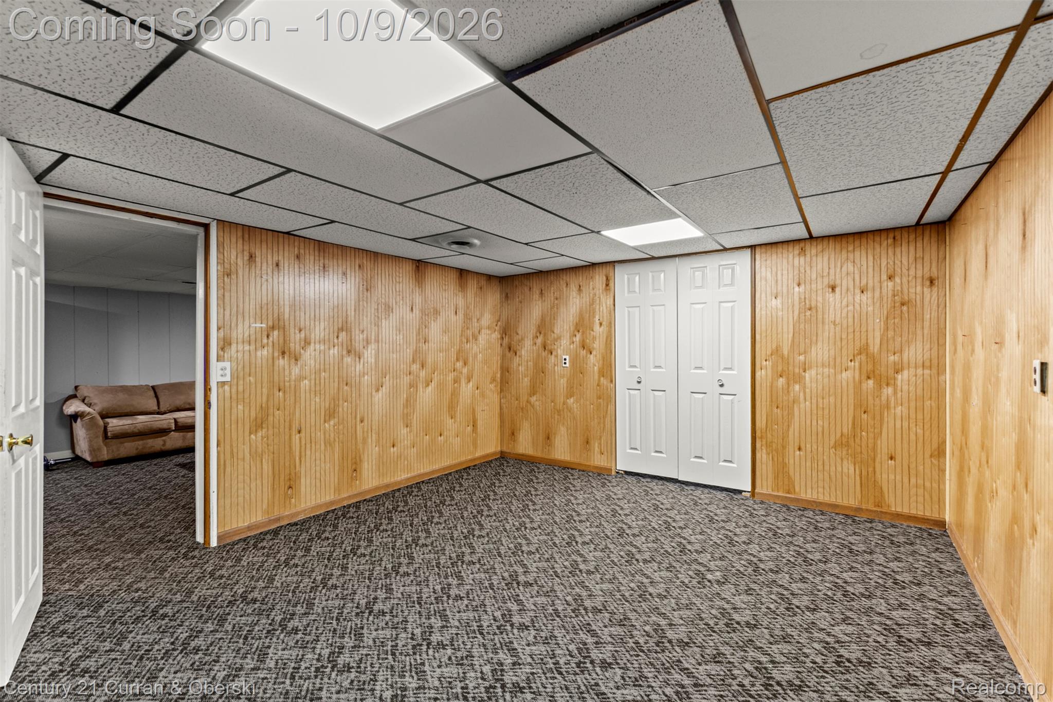 43040 Willis Road Belleville, MI 48111 - Photo 36 of 65 Textured carpet flooring, wood-panel walls, drop ceiling with integrated lighting, and white bi-fold closet doors