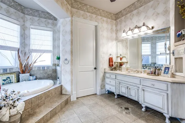 a spacious bathroom with a granite countertop tub sink a mirror a window and vanity