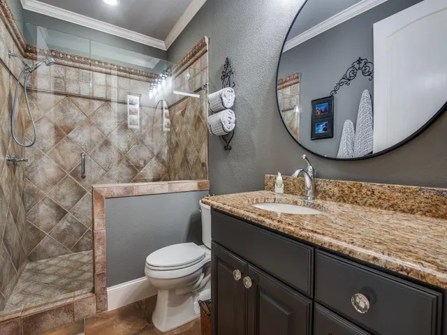 a bathroom with a granite countertop sink mirror vanity and toilet