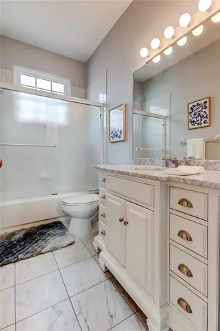 a spacious bathroom with a granite countertop sink a toilet and mirror
