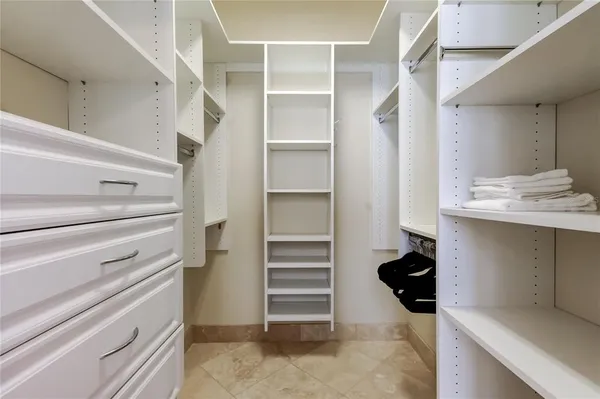 a view of walk in closet with clothes and shoes