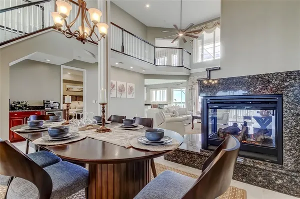 a view of a dining room and livingroom with furniture wooden floor a rug a fireplace and a chandelier