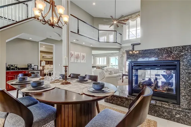 a view of a dining room and livingroom with furniture wooden floor a rug a fireplace and a chandelier