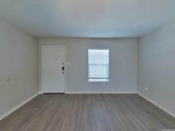 an empty room with wooden floor and window