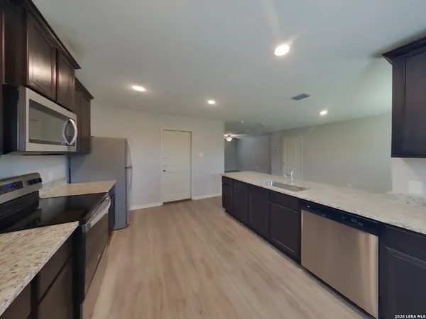 a large kitchen with stainless steel appliances granite countertop a lot of counter space and wooden floor