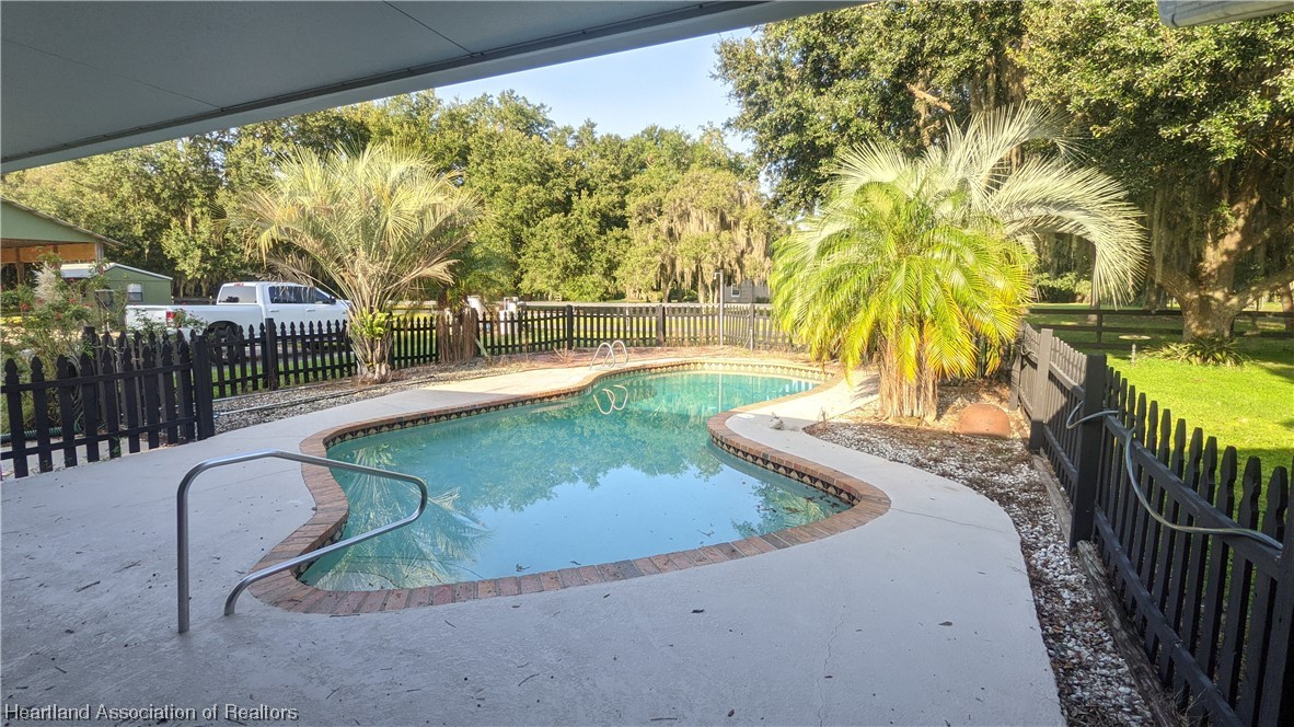 617 Bost Road Wauchula, FL 33873 - Photo 17 of 38 a view of swimming pool with a patio and wooden fence