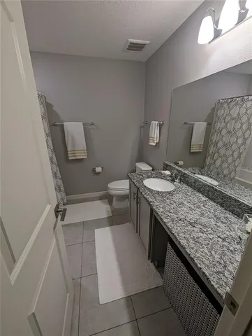 a bathroom with a granite countertop sink and a toilet
