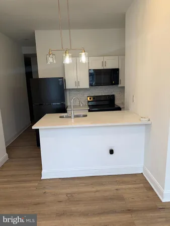 a room with kitchen island a sink and a stove with wooden floor