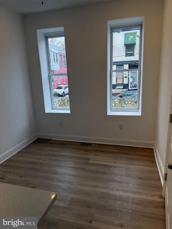 a view of an empty room with window and wooden floor