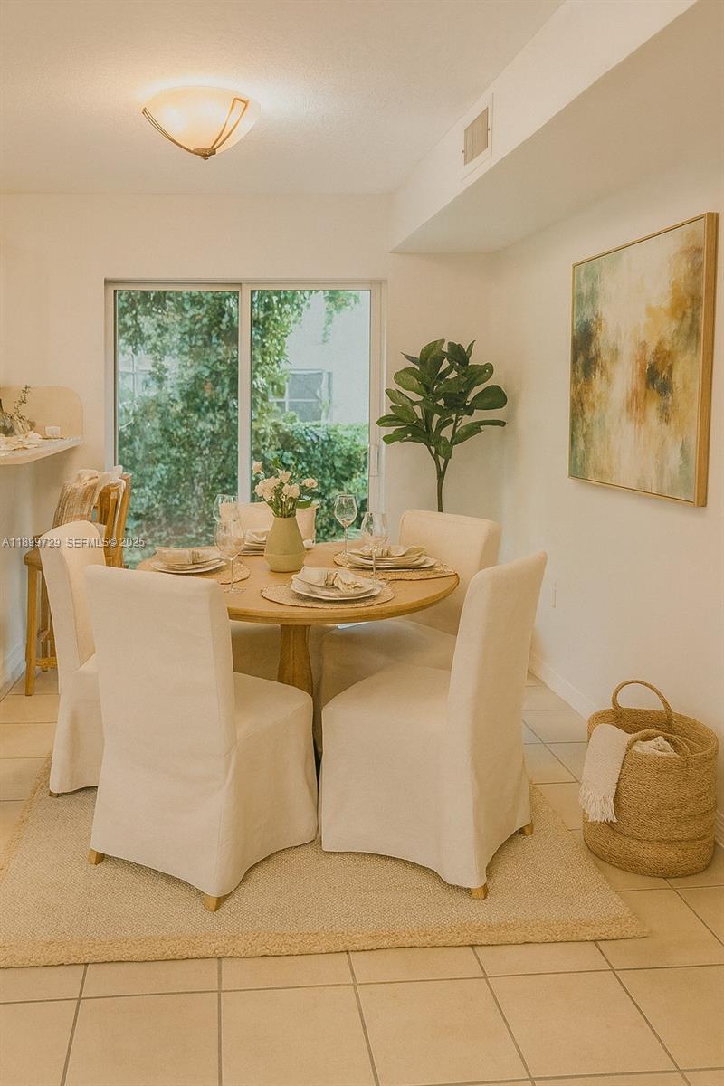 1270 Southeast 28th Court, Unit 101 Homestead, FL 33035 - Photo 13 of 27 a dining room with furniture a window and a potted plant