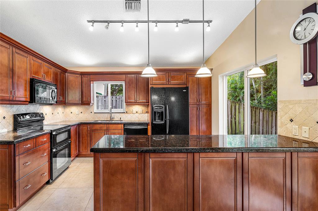 1443 Banyan Circle Pompano Beach, FL 33069 - Photo 3 of 36 a kitchen with stainless steel appliances granite countertop a stove a sink and a refrigerator