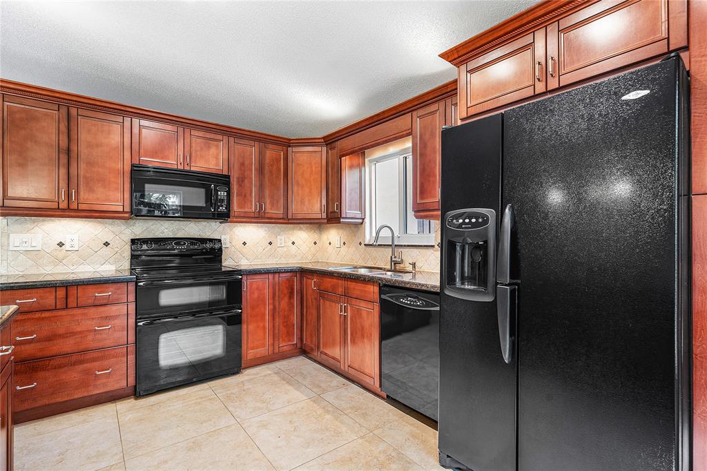 1443 Banyan Circle Pompano Beach, FL 33069 - Photo 5 of 36 a kitchen with stainless steel appliances granite countertop a refrigerator stove and oven