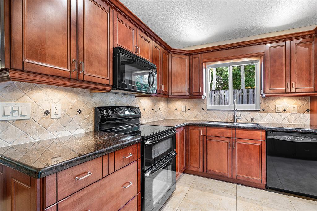 1443 Banyan Circle Pompano Beach, FL 33069 - Photo 6 of 36 a kitchen with stainless steel appliances granite countertop wooden cabinets a sink and a stove