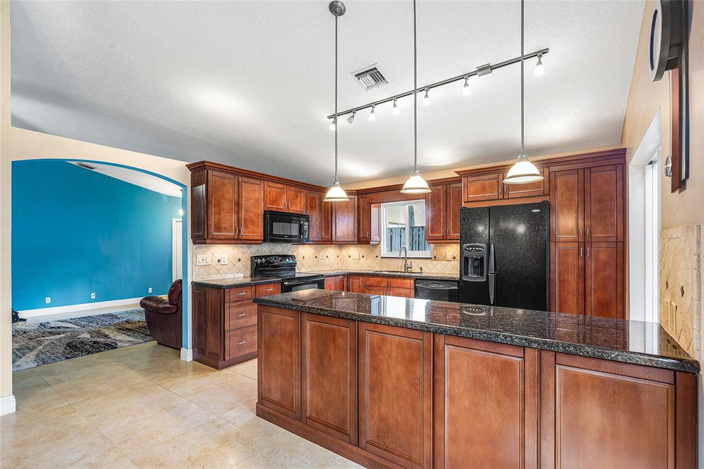 1443 Banyan Circle Pompano Beach, FL 33069 - Photo 10 of 36 a kitchen with stainless steel appliances granite countertop a sink a stove and a refrigerator