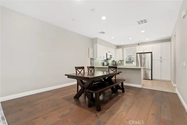 a living room with stainless steel appliances kitchen island hardwood floor and a sink
