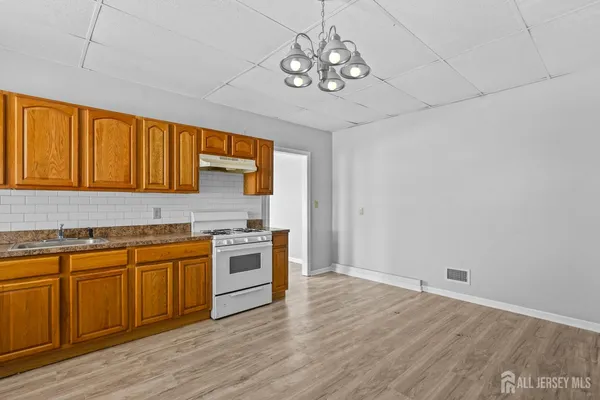 a kitchen with stainless steel appliances granite countertop a sink a stove a refrigerator cabinets and wooden floor