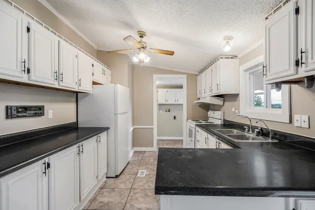 a kitchen with granite countertop a sink stove and cabinets