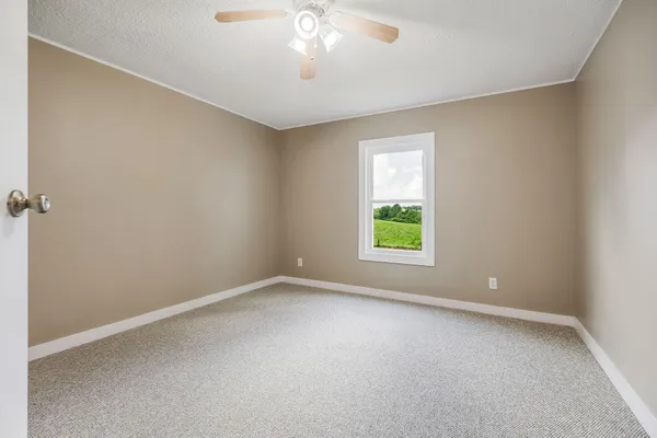 a view of an empty room and chandelier fan