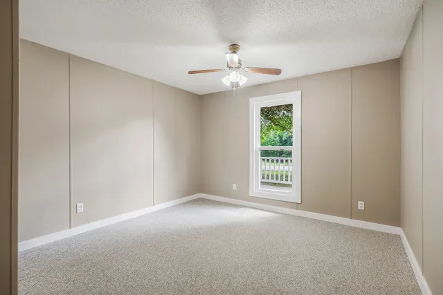an empty room with a chandelier fan and closet area