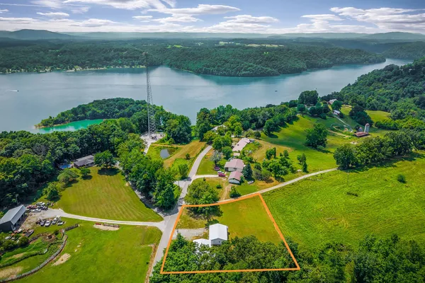 an aerial view of a residential houses with outdoor space and a lake view