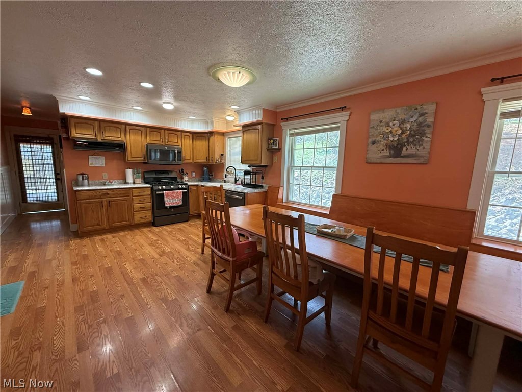 7170 Old Town Road Mount Perry, OH 43760 - Photo 9 of 41 Kitchen featuring wood finish cabinetry, light countertops, a textured ceiling, gas stove, and light wood finished floors