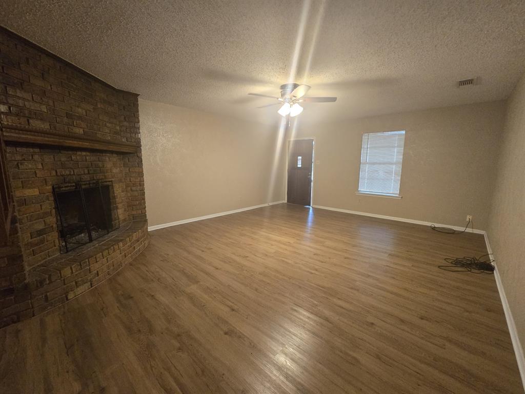 3101 Professional Drive, Unit A Corsicana, TX 75110 - Photo 1 of 7 an empty room with wooden floor fireplace and fan