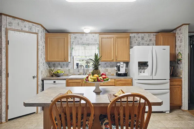 a view of kitchen with stainless steel appliances granite countertop a stove top oven a sink and a refrigerator
