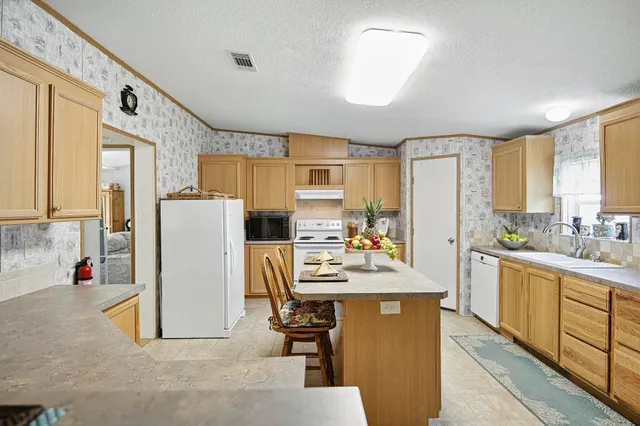 a kitchen with stainless steel appliances a refrigerator a sink dishwasher a oven with white cabinets and wooden floor