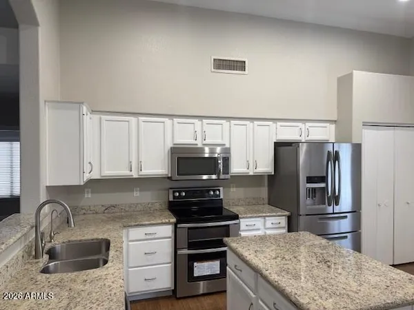 a kitchen with granite countertop a refrigerator stove and sink
