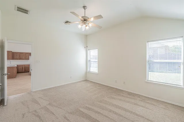 an empty room with windows and chandelier fan