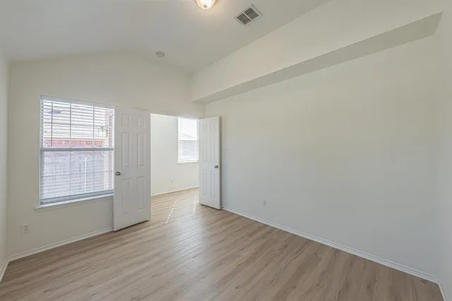 an empty room with wooden floor and windows