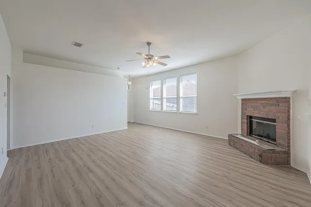 an empty room with wooden floor fireplace and windows