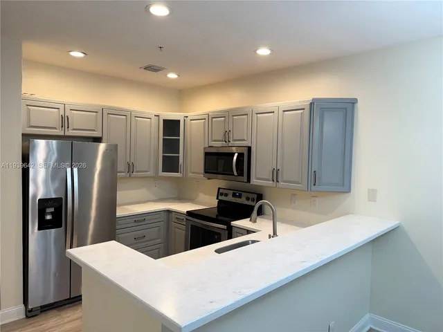 a kitchen with stainless steel appliances a refrigerator sink and microwave