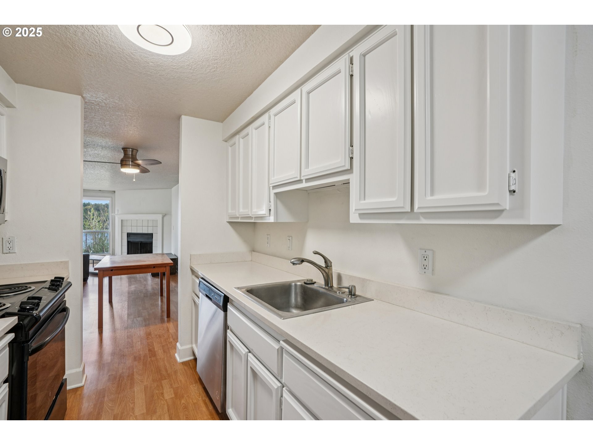 5620 South Riverside Lane, Unit 5 Portland, OR 97239 - Photo 13 of 39 a kitchen with white cabinets a sink dishwasher and a stove with wooden floor