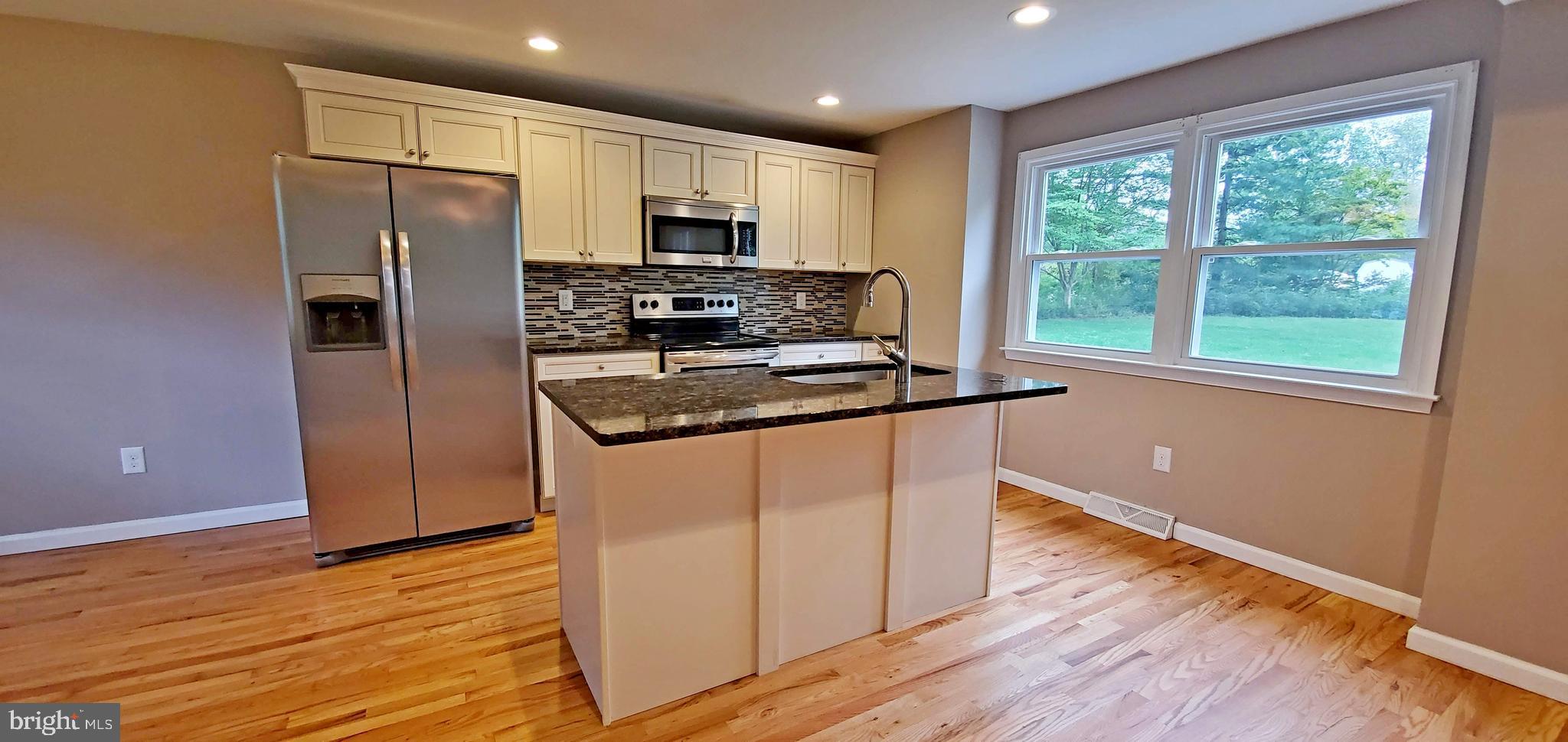 a kitchen with kitchen island granite countertop stainless steel appliances a refrigerator microwave and stove
