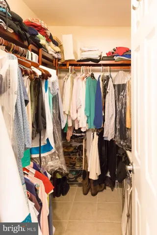 a view of walk in closet with clothes and shoes