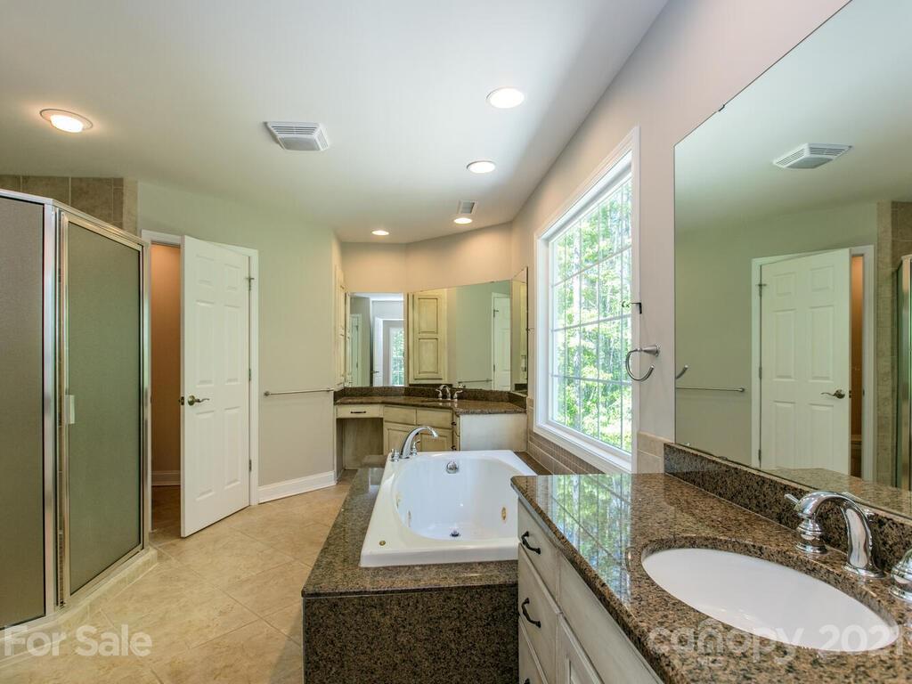 356 Green Hills Road Mill Spring, NC 28756 - Photo 18 of 31 a bathroom with a granite countertop sink a toilet a mirror and shower