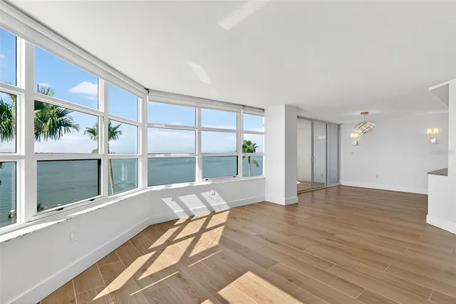 a kitchen with stainless steel appliances granite countertop a stove top oven a sink dishwasher a refrigerator and a dining table with wooden floor