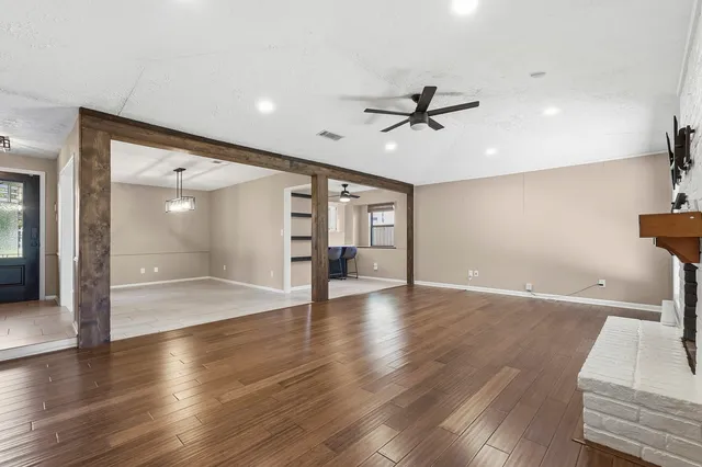 a view of an empty room with wooden floor and a ceiling fan