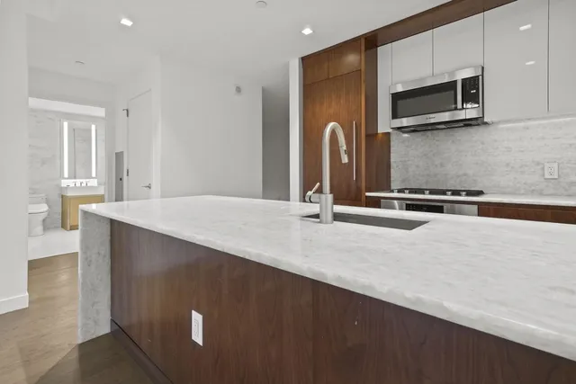 a kitchen with kitchen island a counter top space appliances and a sink
