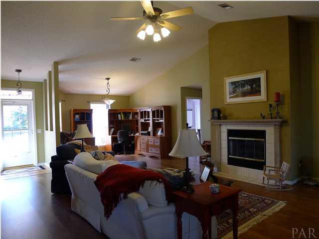 4890 Timber Ridge Drive Pace, FL 32571 - Photo 4 of 18 a living room with furniture a fireplace and a chandelier