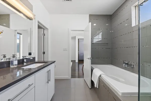 a bathroom with a granite countertop tub sink and mirror