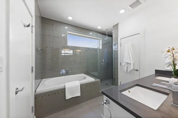 a bathroom with a tub sink a mirror and a shower