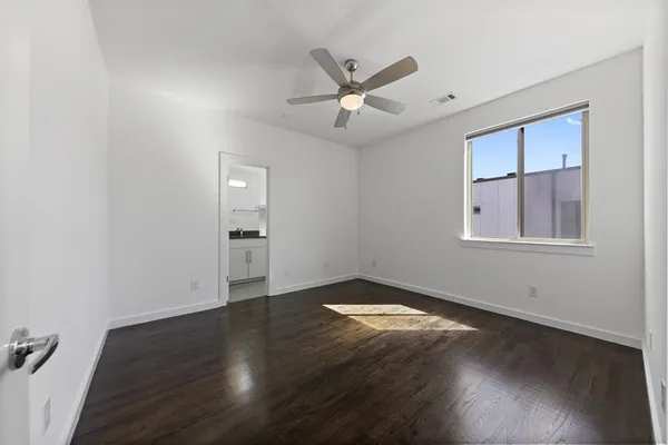 a view of an empty room with wooden floor and a window