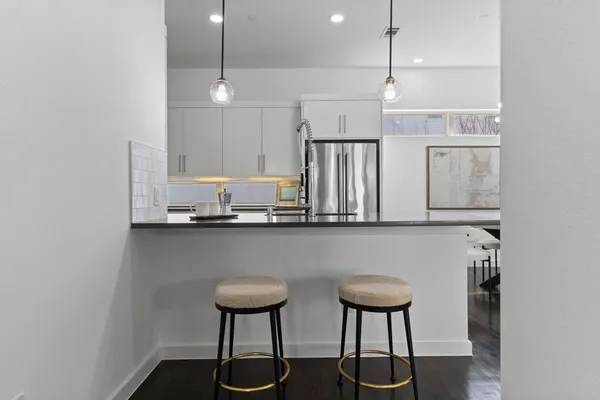 a kitchen with stainless steel appliances granite countertop a sink a stove a refrigerator and white cabinets with wooden floor